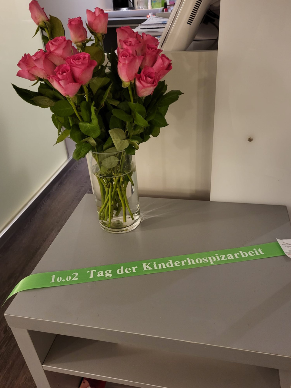 Tisch mit grünem Band und Rosen in einer Vase