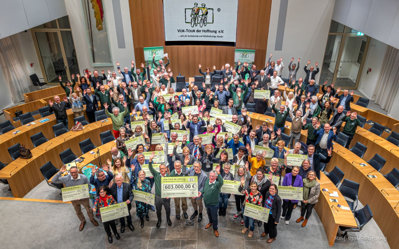 viele Menschen im Mainzer Landtag, die einen Scheck in die Luft halten