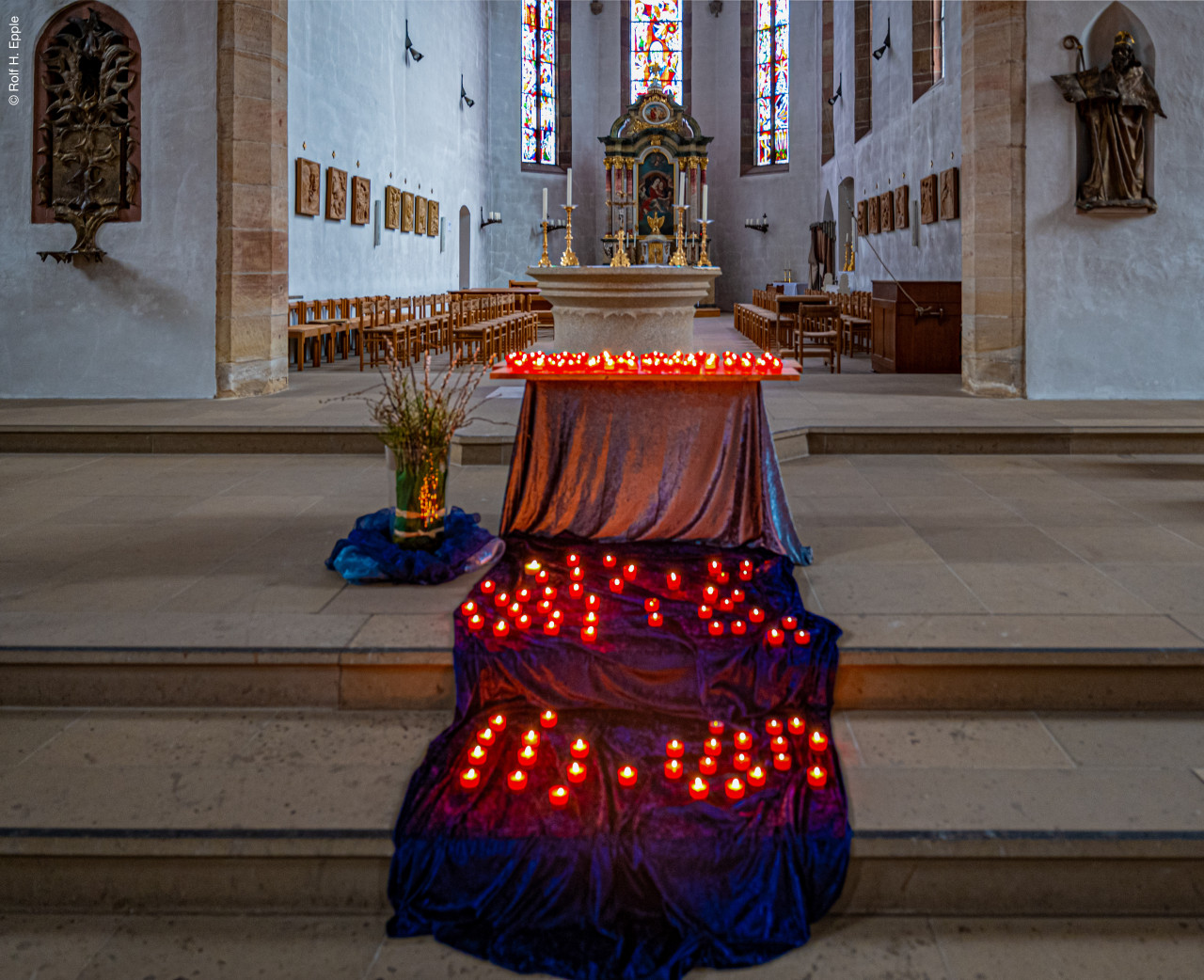 ein geschmückter Altar mit vielen Teelichtern davor